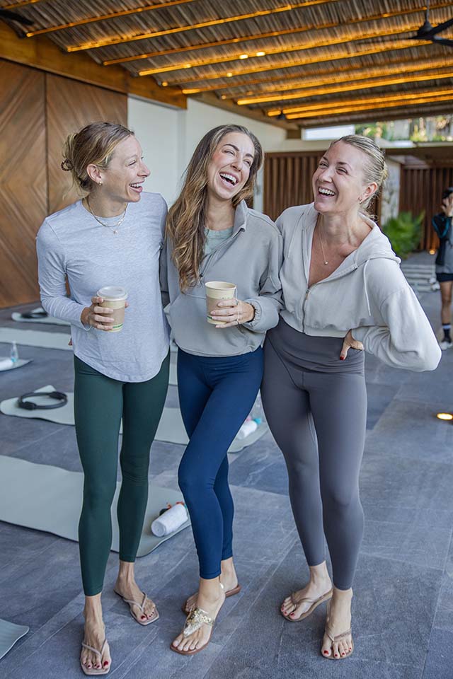 Three women laughing together after a Pilates class